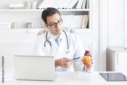 Close up of heart mockup with male doctor pointing to it and explaining the structure. Cardiology and healthcare concept photo