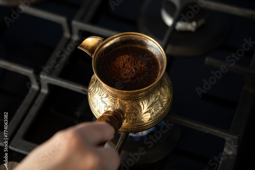 Close up shot of preparation of turkish coffee using copper cezve on the gas stove	
