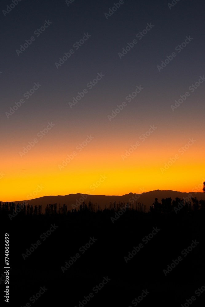 Beautiful vertical view of clear sky during orange sunset over hills Beautiful vertical view of clear sky during orange sunset over hills