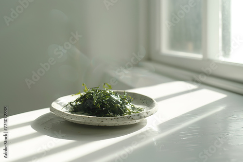 A plate with green salad made from chukka seaweed on a wooden table, illuminated by bright sunlight. Vegan seafood. photo