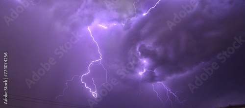 Panoramic view of lightning illuminating the dark purple cloudy sky
