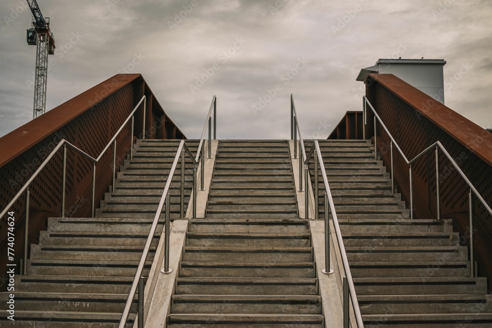Stairway leading onto a bridge with wooden railings under a dark gray sky on a gloomy day Stairway leading onto a bridge with wooden railings under a dark gray sky on a gloomy day