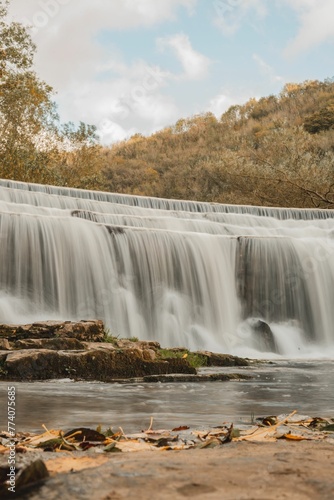 Vertical shot of a picturesque waterfall against a fall forest