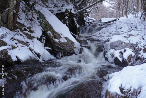 Waterfall surrounded by rocks covered with snow in winter