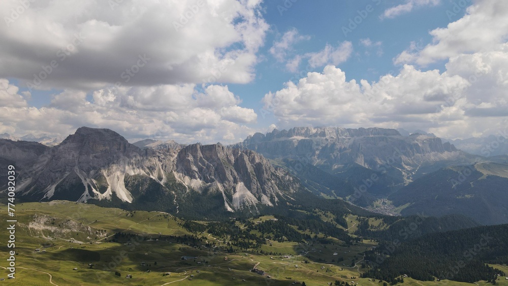Aerial shot of Seceda Mountain and a vast valley with floating clouds above in the Alps of Italy Aerial shot of Seceda Mountain and a vast valley with floating clouds above in the Alps of Italy