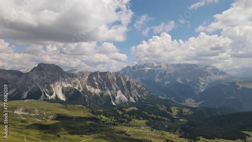 Aerial shot of Seceda Mountain and a vast valley with floating clouds above in the Alps of Italy