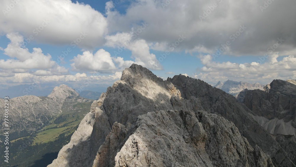 Aerial shot of the Seceda Mountain peak with floating clouds above in the Alps of Italy Aerial shot of the Seceda Mountain peak with floating clouds above in the Alps of Italy