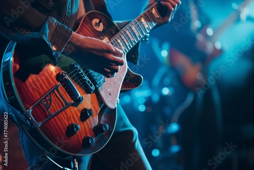 Close-up of a musician playing electric guitar on stage with vibrant stage lighting.