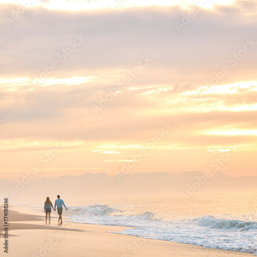 Rear View Of Couple In Casual Clothing On Vacation Holding Hands Walking Along Beach Shore At Dawn