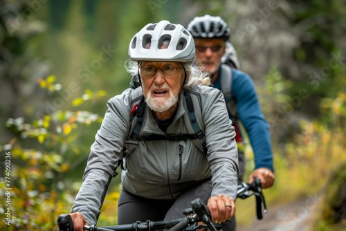 A senior man and woman equipped with helmets, riding bikes on a trail in a natural setting