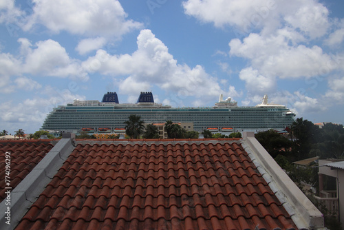 Cruise liner over the roofs of the Bonairian houses against blue sky with white clouds, Bonaire, Caribbean Netherlands photo