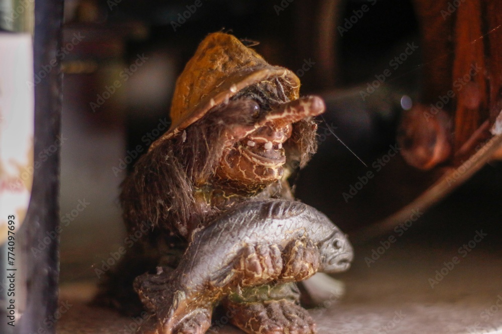Old figurine of trolls, holding a fish in hands on a blurry background