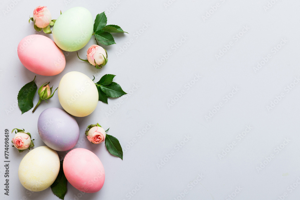 Happy Easter. Easter eggs on colored table with yellow roses. Natural dyed colorful eggs background top view with copy space