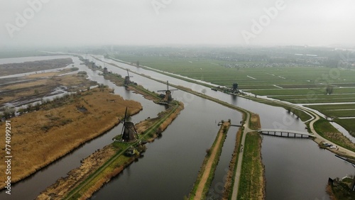 Aerial shot of the Windmills at Kinderdijk and a bridge on a river in a foggy weather