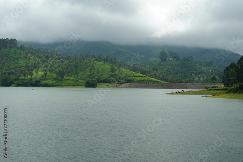 Lake near a lush green hillside with trees