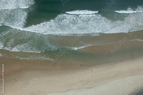 Aerial of sea tidal waves coming towards the shore on a sunny day photo