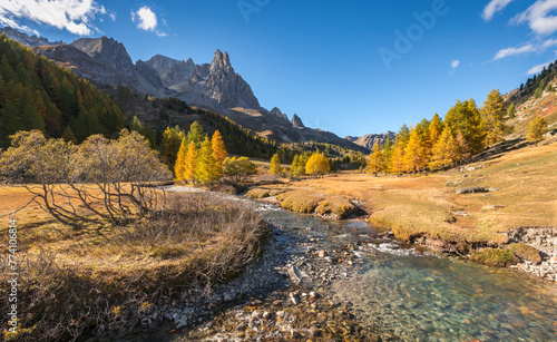 Autumn in Claree Valley in the French Alps with larch trees. Claree river and Main de Crepin mountain peak. Cerces Massif in Hautes Alpes, France