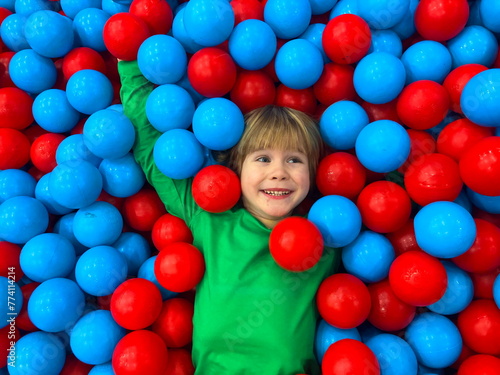 Cute smiling boy in ball pool looking at camera