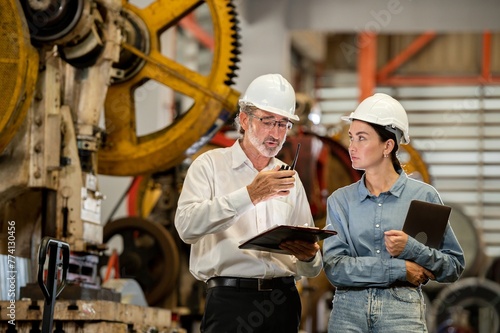 partner woman engineer assistant in helmet inspection check heavy machine construction installation in industrial metal roof roll sheet factory with colleague manager. partnership operation factory