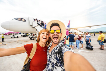 Happy couple of tourists boarding on a plane at the airport - Happy man and woman having happy summer vacation together - Transportation and holidays concept