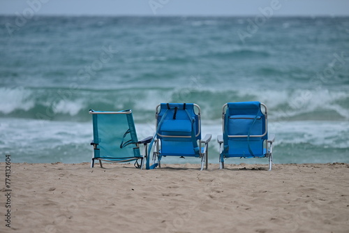 Three abandoned deck chairs at the beach of Benidorm-Spain on a warm and stormy April day. 