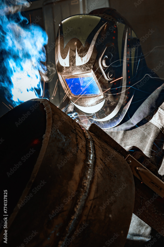 A welder diligently works in a factory, sparks flying as they expertly weld metal, showcasing skill and precision in their craft.
