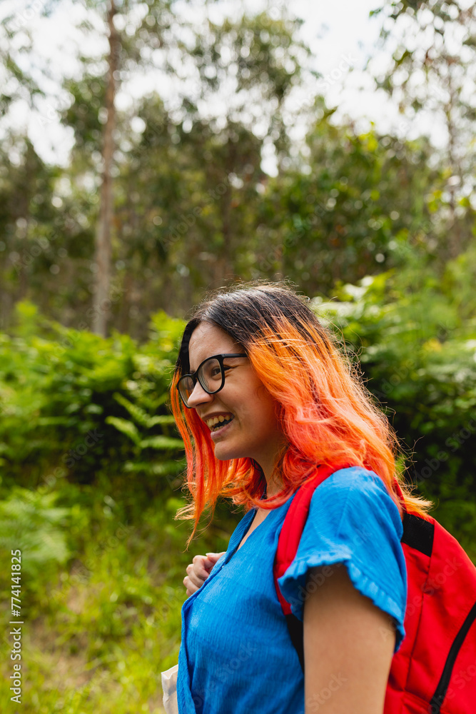 A young girl with orange hair smiles during a walk in a natural area in summer A young girl with orange hair smiles during a walk in a natural area in summer