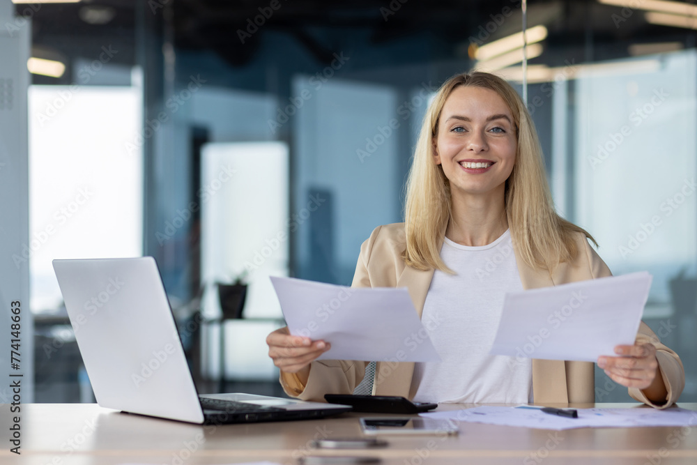 Professional businesswoman reviewing documents at her desk Professional businesswoman reviewing documents at her desk