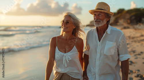 Happy mature retired couple walking on the beach at sunset. Enjoying your free time as a senior.