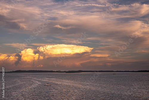 Miami, Florida, USA - July 29, 2023: Mushroom sunset cloud over Virginia Key island, forested green shoreline. Wastewater treatment plant in center, Motor yacht upfront