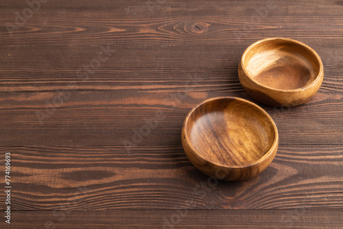 Two empty brown wooden bowl on brown wooden. Side view, copy space