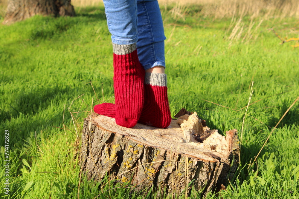 A person wearing red boots and red socks standing on a log in the grass A person wearing red boots and red socks standing on a log in the grass