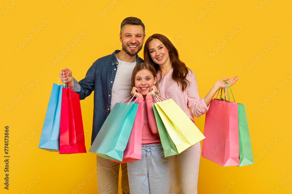 Family showing shopping bags and smiling widely Family showing shopping bags and smiling widely