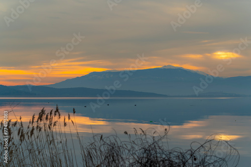 Fototapeta Naklejka Na Ścianę i Meble -  Balıkesir Lake Manyas at sunset boats reflection vegetation cloudy sky