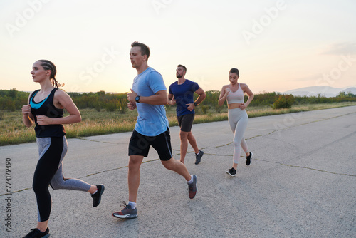 A diverse group of runners trains together at sunset.