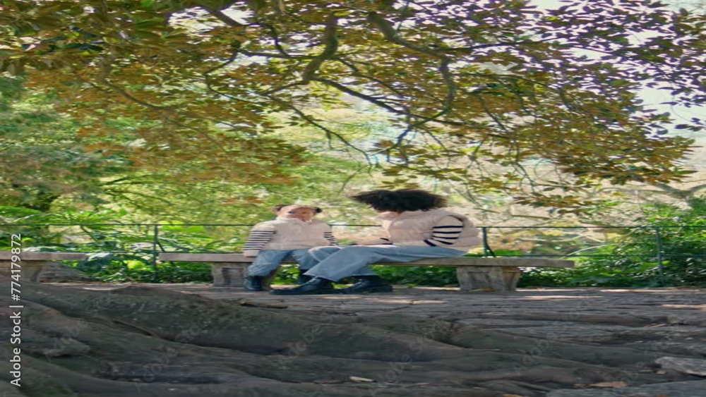 Unrecognizable mother daughter sitting on park bench looking on tree vertical. Unrecognizable mother daughter sitting on park bench looking on tree vertical.