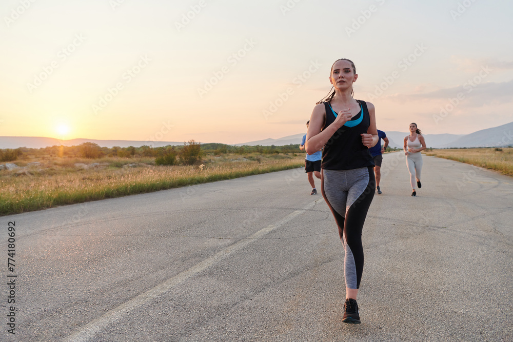 A diverse group of runners trains together at sunset. - obrazy, fototapety, plakaty 