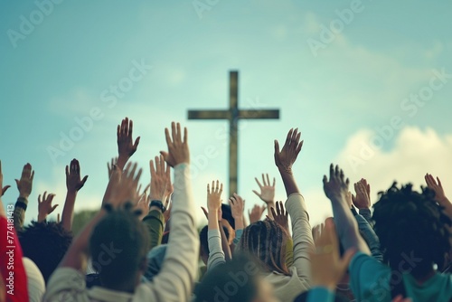 A diverse community of individuals with raised hands in worship towards a Christian cross photo