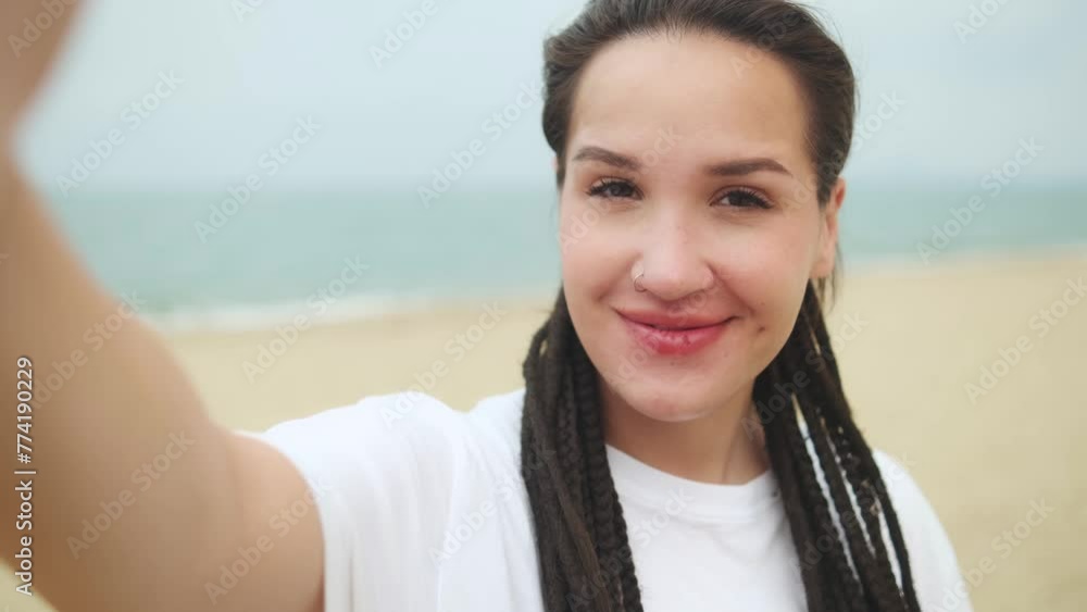 Young caucasian pretty woman showing sign V, heart. making selfie with happy smile with ocean beach on background Young caucasian pretty woman showing sign V, heart. making selfie with happy smile with ocean beach on background