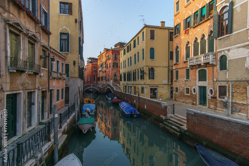 Typical narrow canal surrounded by buildings with boat in Venice, Veneto, Italy