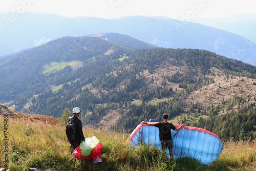 two people preparing on a meadow to take off with there paragliding parachute