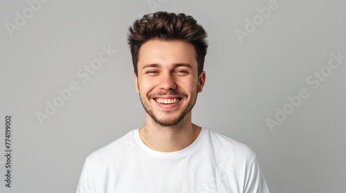 Smiling young caucasian man wearing white t-shirt, isolated on gray background © NadiaArts