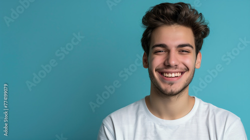 Smiling young caucasian man wearing white t-shirt, isolated on blue background