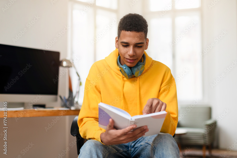Young man reading a notebook at a home office desk Young man reading a notebook at a home office desk