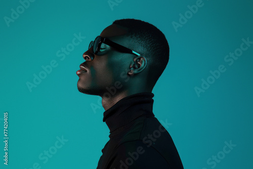 A conceptual image showcasing a male profile in a turtle neck against a teal backdrop, focusing on form and color photo