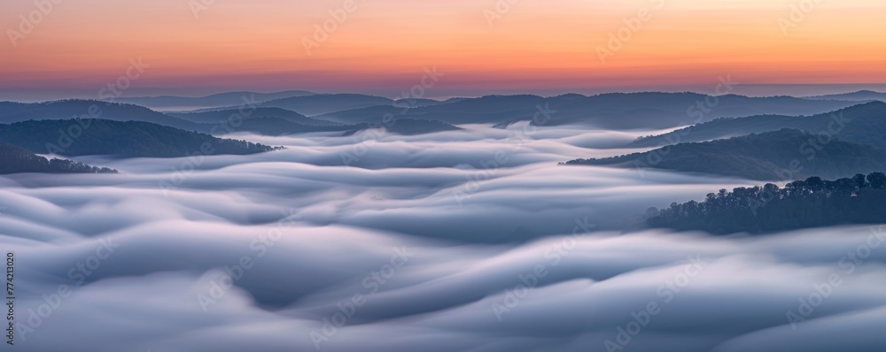 Waves of fog roll over hills at dawn