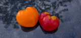 Two tomatoes in shape of heart on gray background.