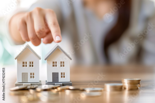 Strategic choice of investing in property, A person compares two miniature house models, symbolizing the decision-making process in real estate investment.