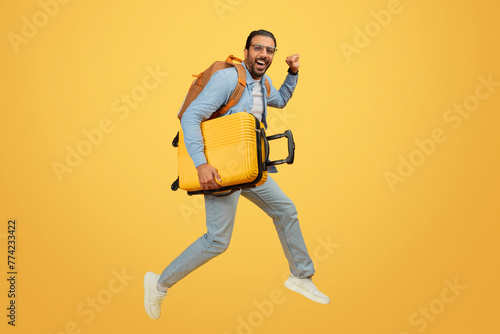 Man jumping with suitcase over yellow background photo