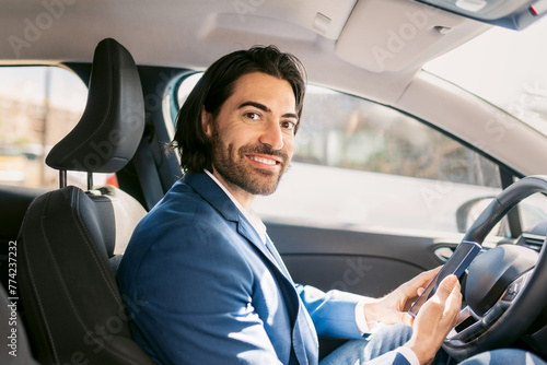 Smiling Businessman sitting in the car Using Smartphone to Navigate on Business Trip